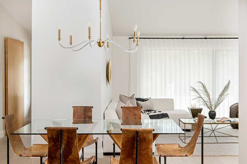 open concept dining living room in small home with white neutral shades and gold chandelier